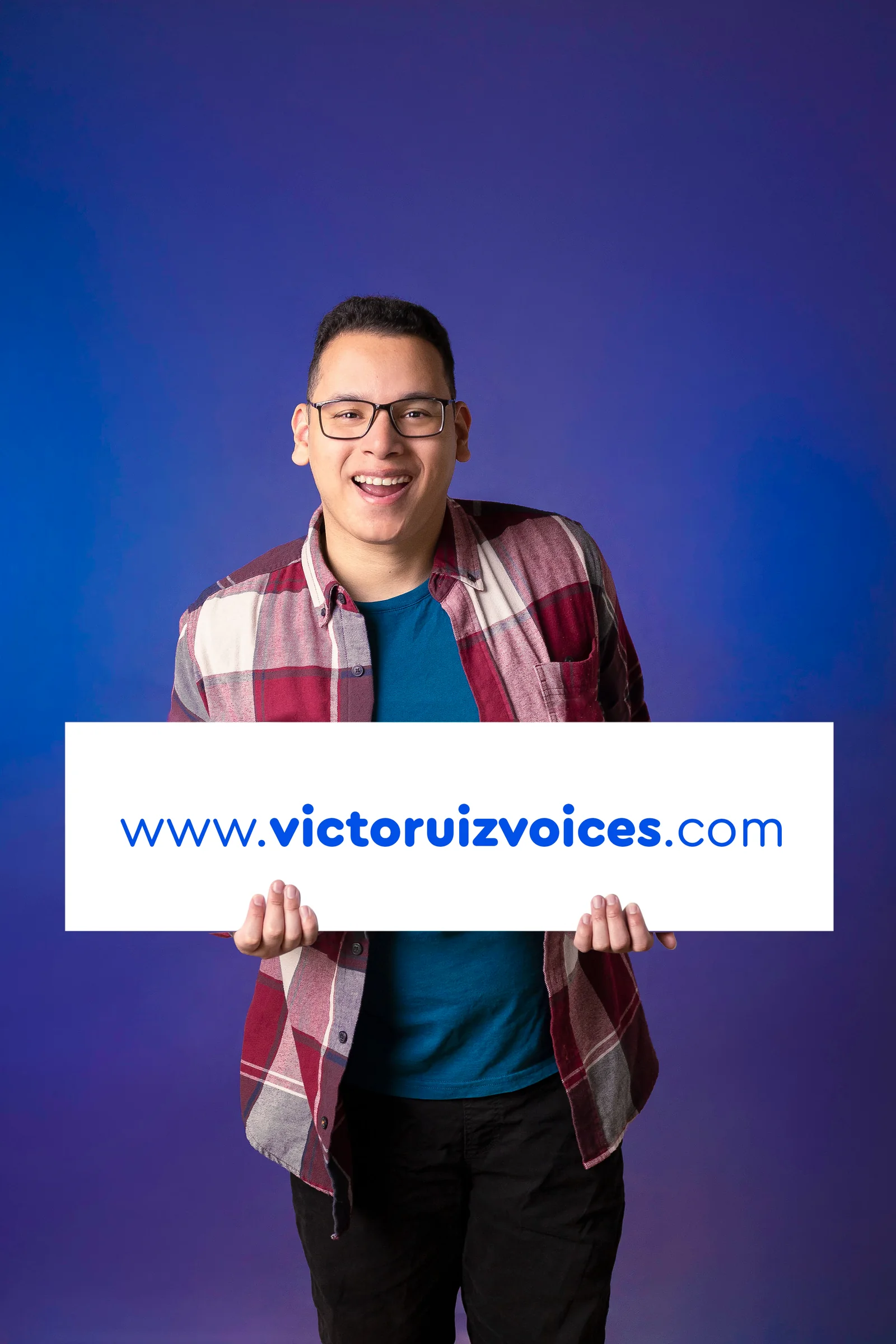 Victor Ruiz sosteniendo un cartel con la dirección victoruizvoices.com